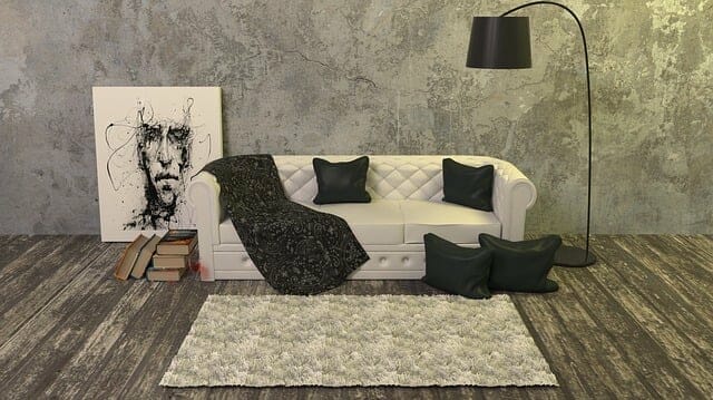 biała kanapa z czarną narzutą i poduszkami, obok lampa